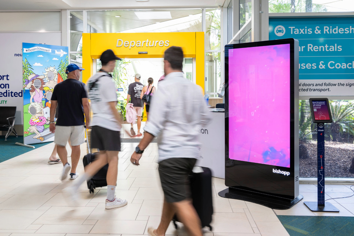 Passengers leaving Sunshine Coast Airport and walking past digital billboard
